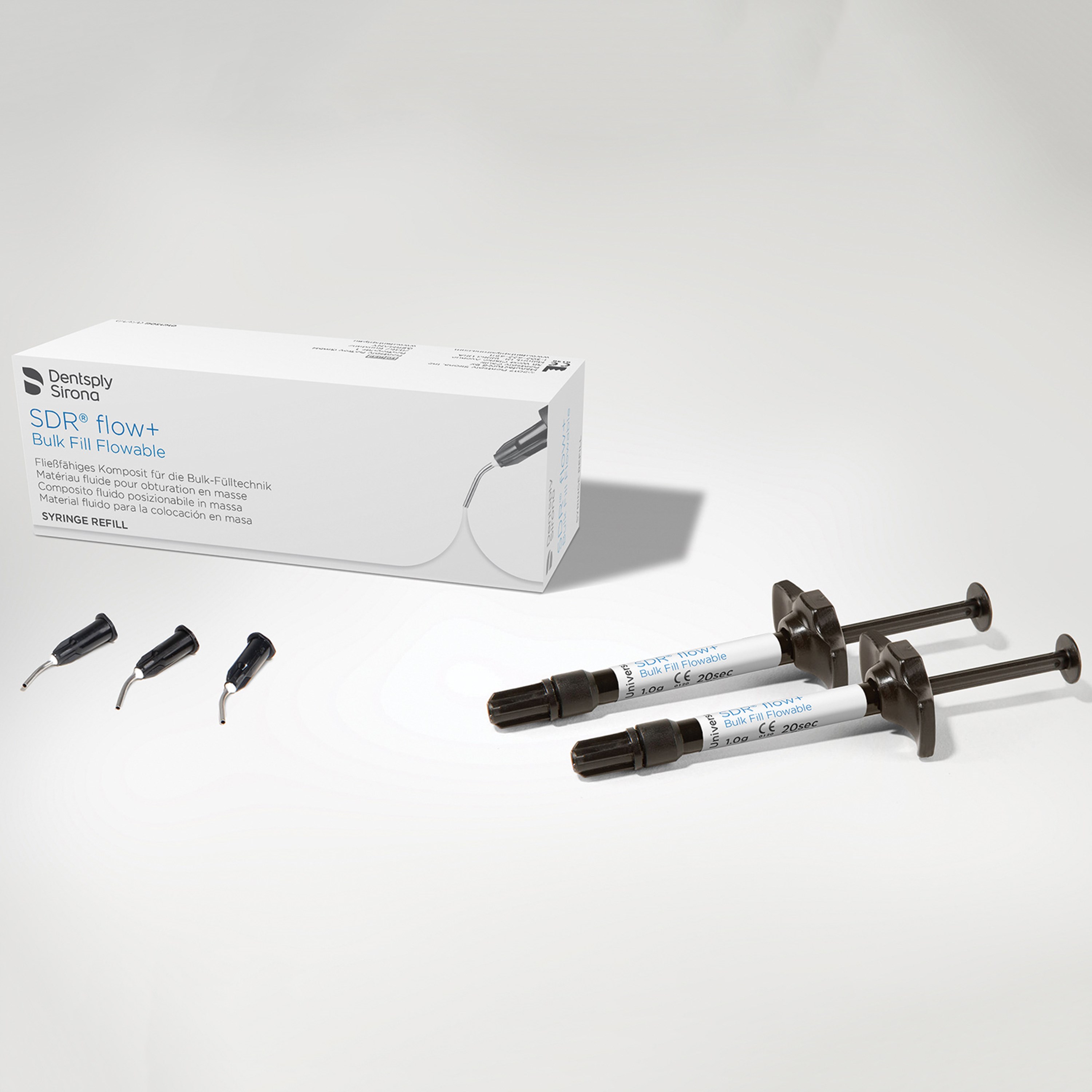 SDR+ Bulk Fill Composite on a blank white background, applicator tips and syringes are placed near its packaging