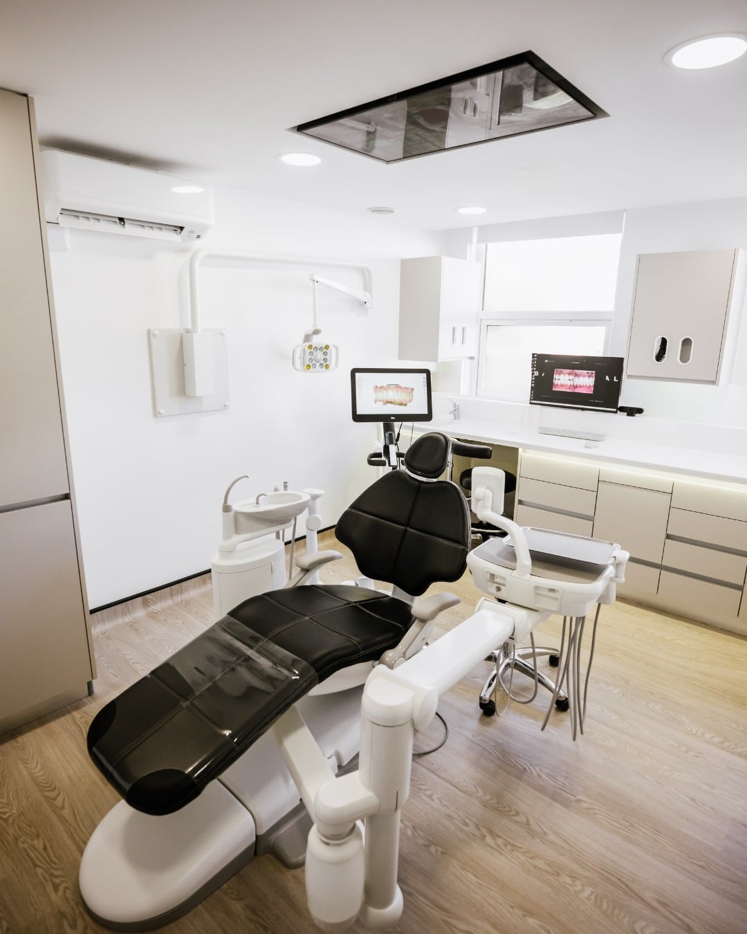 A sleek back dental chair in the middle of a beautifully-furnished practice room